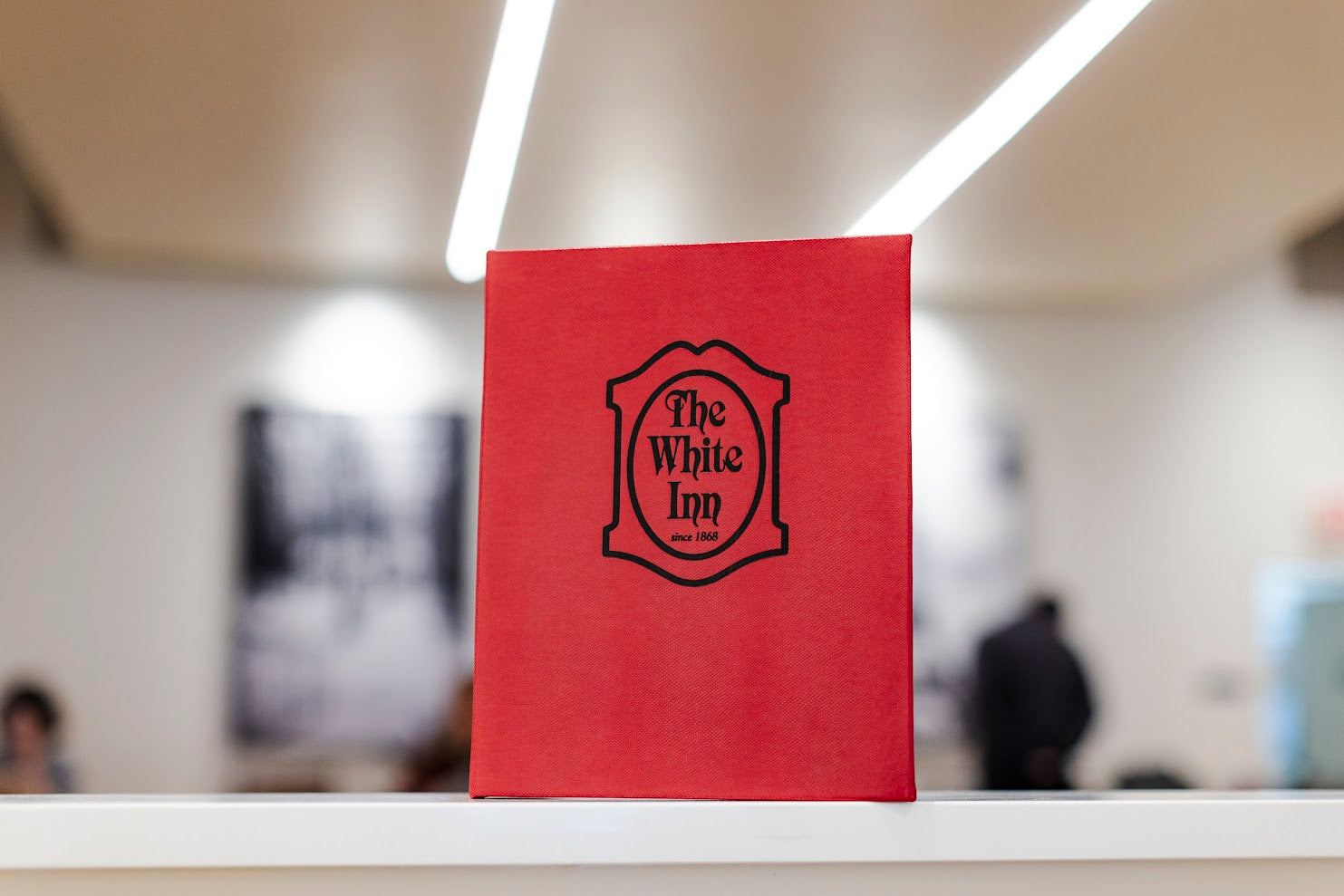 Red Rio material menu cover with "The White Inn" logo in black foil.